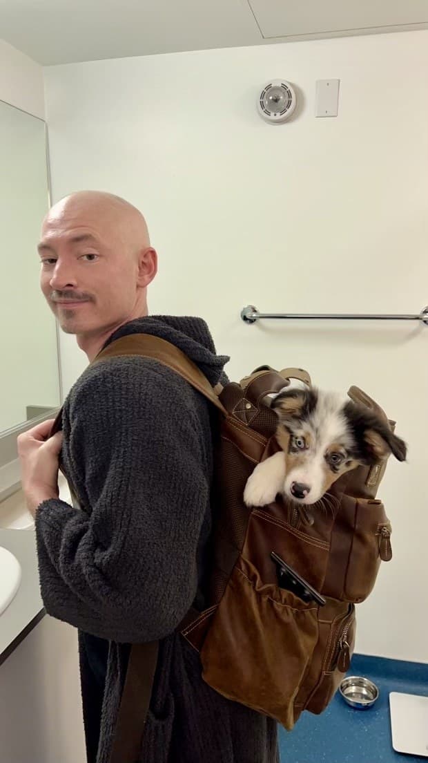 Bald Kimmer O'Reilly carrying young Casper, his service dog, during cancer treatment